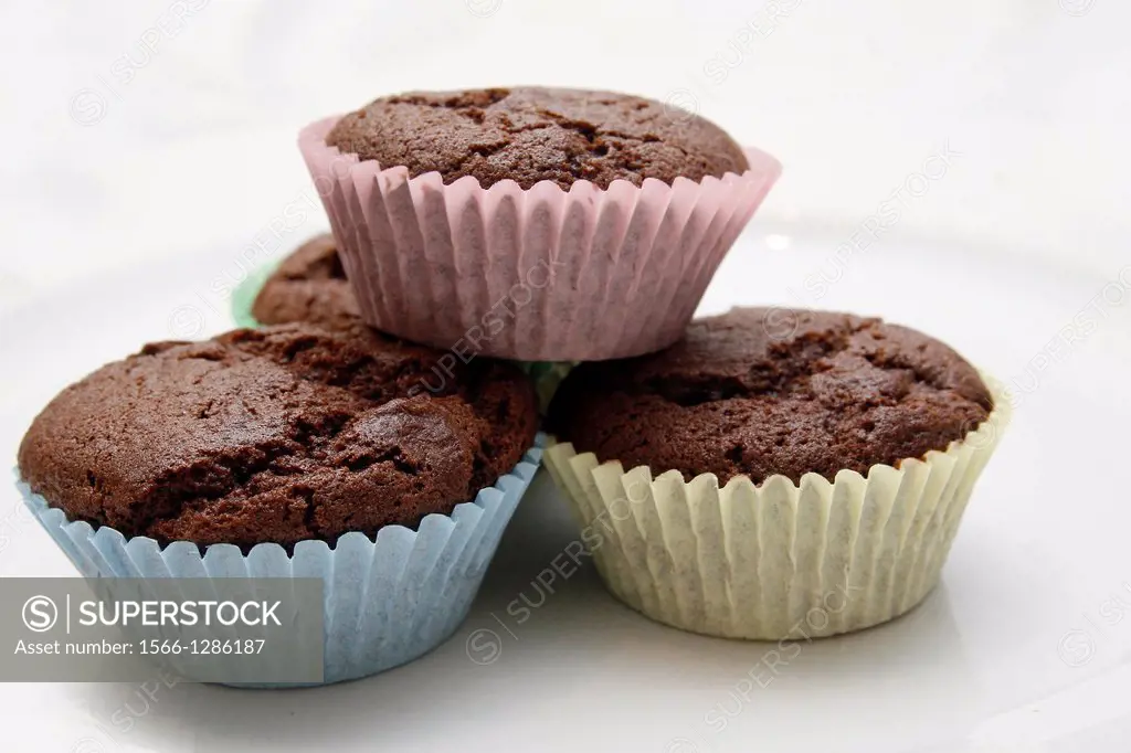 chocolate cupcakes in multicoloured bun cases on white plate.