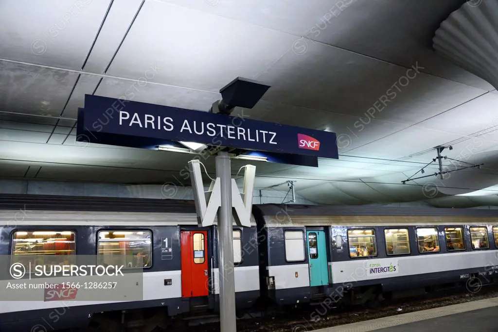 France, Paris, train station platform, Austerlitz train station, plate with name - Paris Austerlitz, train full of passengers in the background
