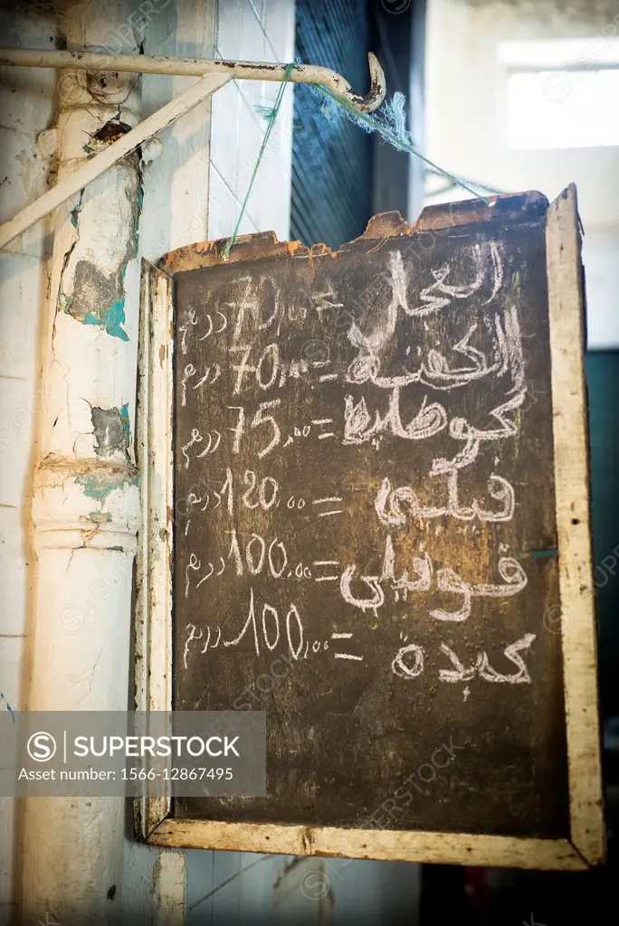 An old board hanging on a hook with arabic hand writing prices. The Nouvelle Ville Market, Fez, Morocco, Africa
