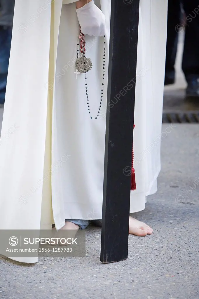 Barefoot penitent doing penance with a wood cross in a Holy week procession, Friday Holy, Linares, Jaen province, Spain.