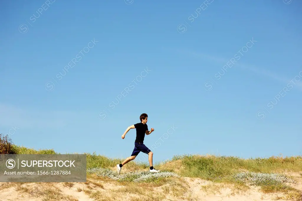 Young adult running in the dunes.