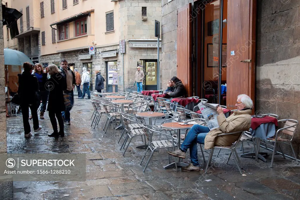 Man Reading Newspaper in Florence, Italy in Winter Rain just off the Ponte Vecchio Bridge.