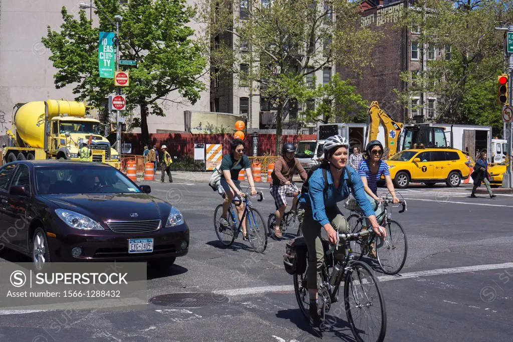 Cyclists maneuver through traffic on bicycles in the Lower East Side neighborhood of New York