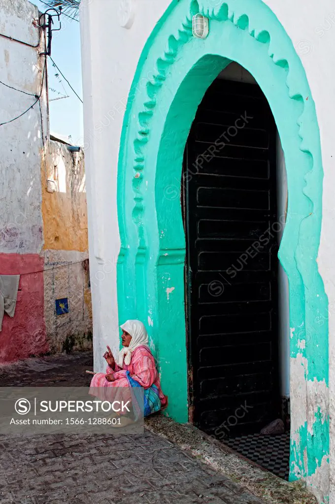 Woman sitting at a moroccan gate in Azemmour medina, Morocco.