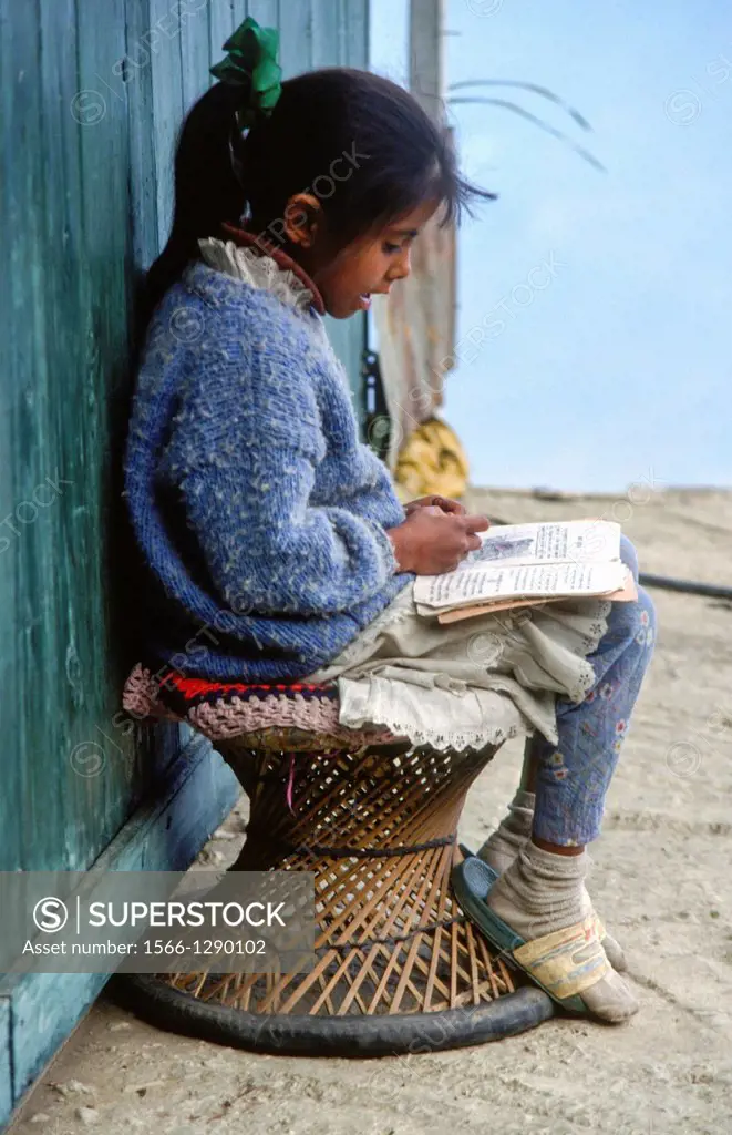 girl doing homework outside her house in Darjeeling, India