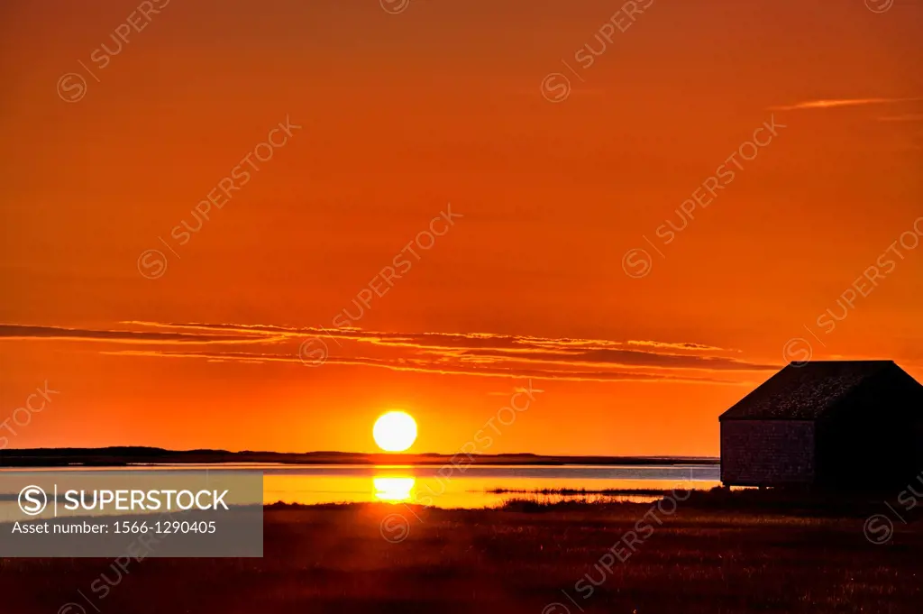Sunrise over salt pond with boat house silhouette, Eastham, Cape Cod, MA, USA.