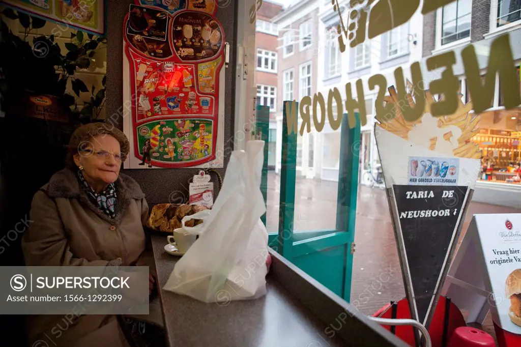 old dutch lady eating chips in a bar, Holland.