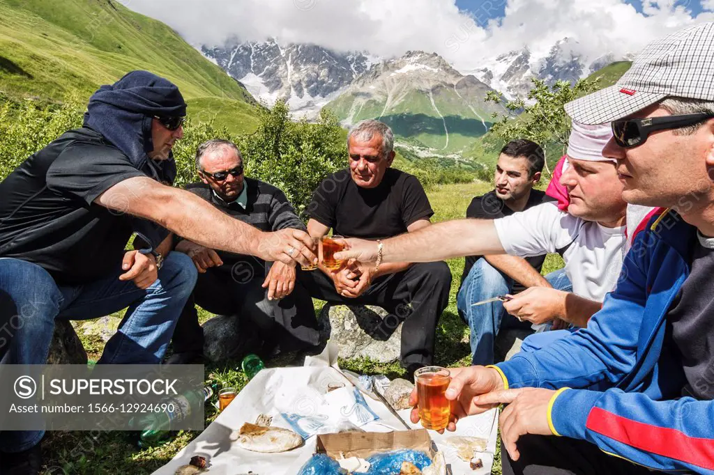 Georgian men drinking wine and toasting in the countryside near Ushguli, the highest permanently inhabited village in Europe. Upper Svanetia, Georgia.