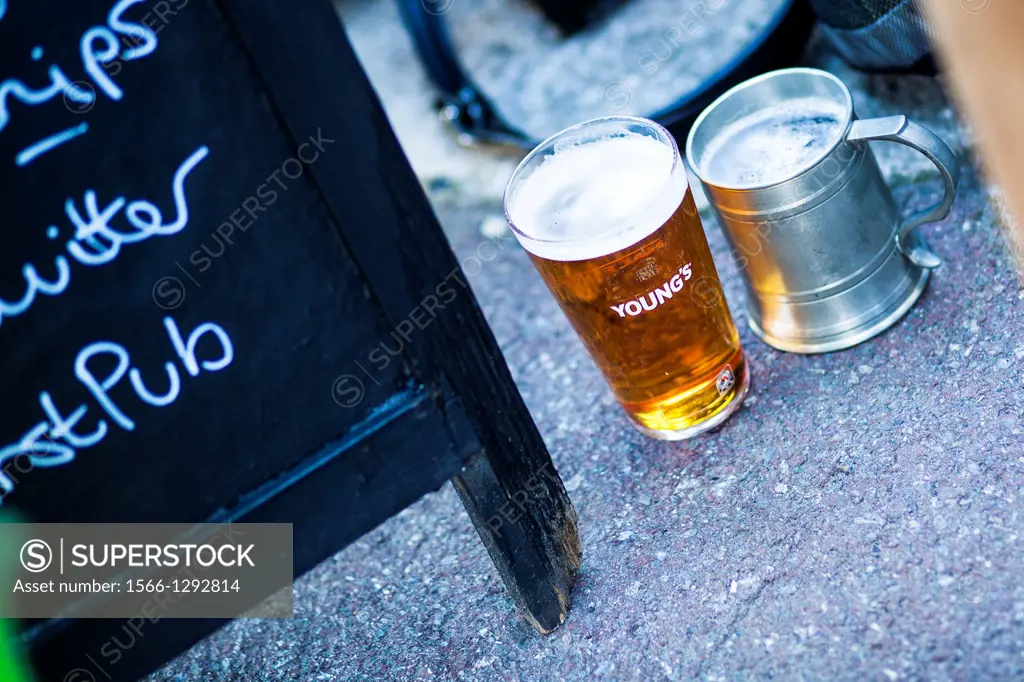 Old and new jug/mug beer pints next to a pub sign, London, UK