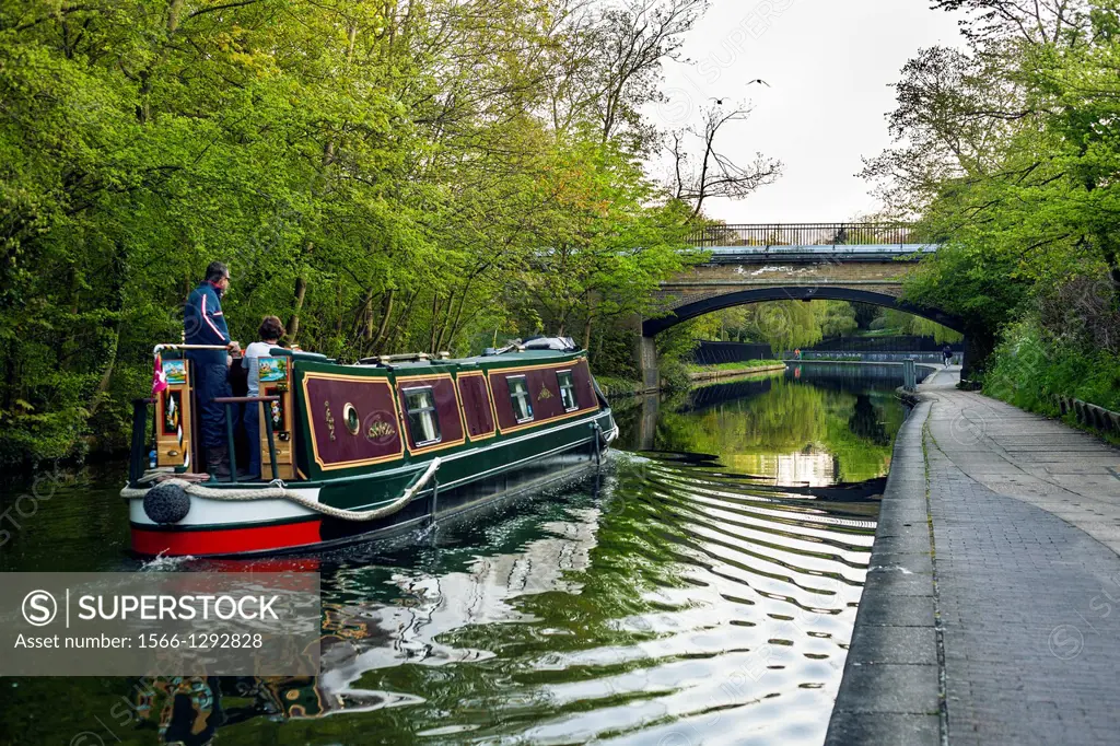 Boat navigating along Regents canal, next to Regents Park, London, UK
