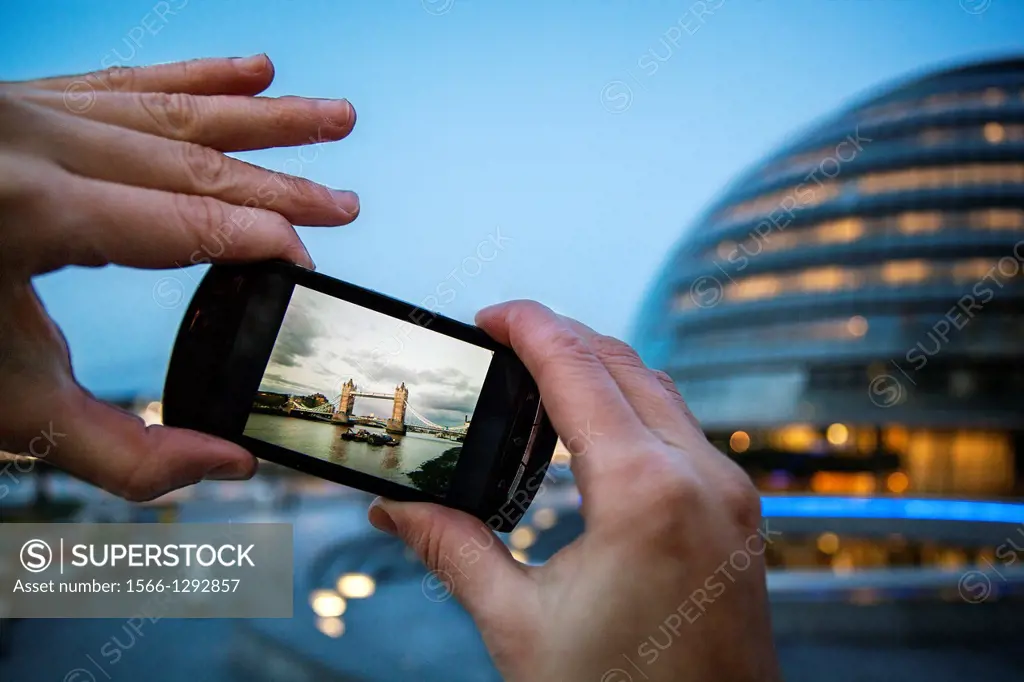Detail of hands Taking a picture of Tower Bridge with a mobile phone, London, UK