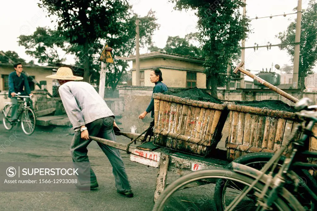 Man pulling cart filled with charcoal. Guangzhou. China