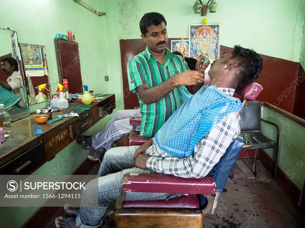 A man gets his beard shaved in a barbershop in Bangalore, Karnataka, India.