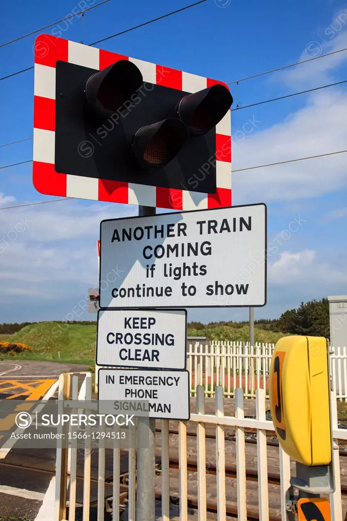 Warning signs. traffic control lights and emergency telephone at the side of a railway crossing, near Irvine, Ayrshire, Scotland.