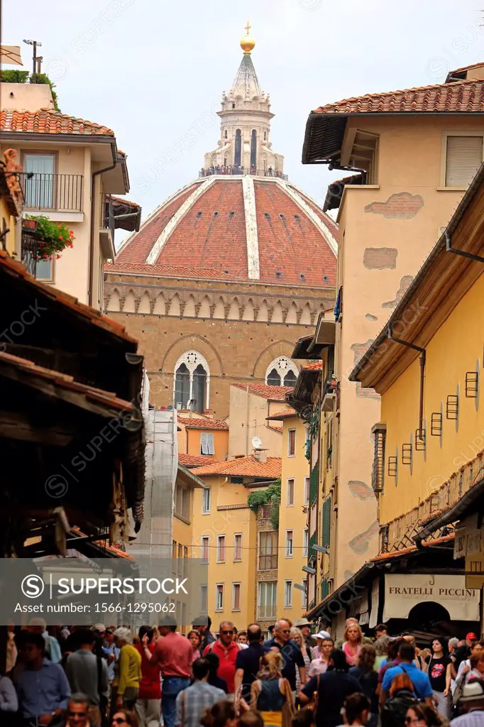 Tourists walking along a street in Florence with the Duomo in the background.