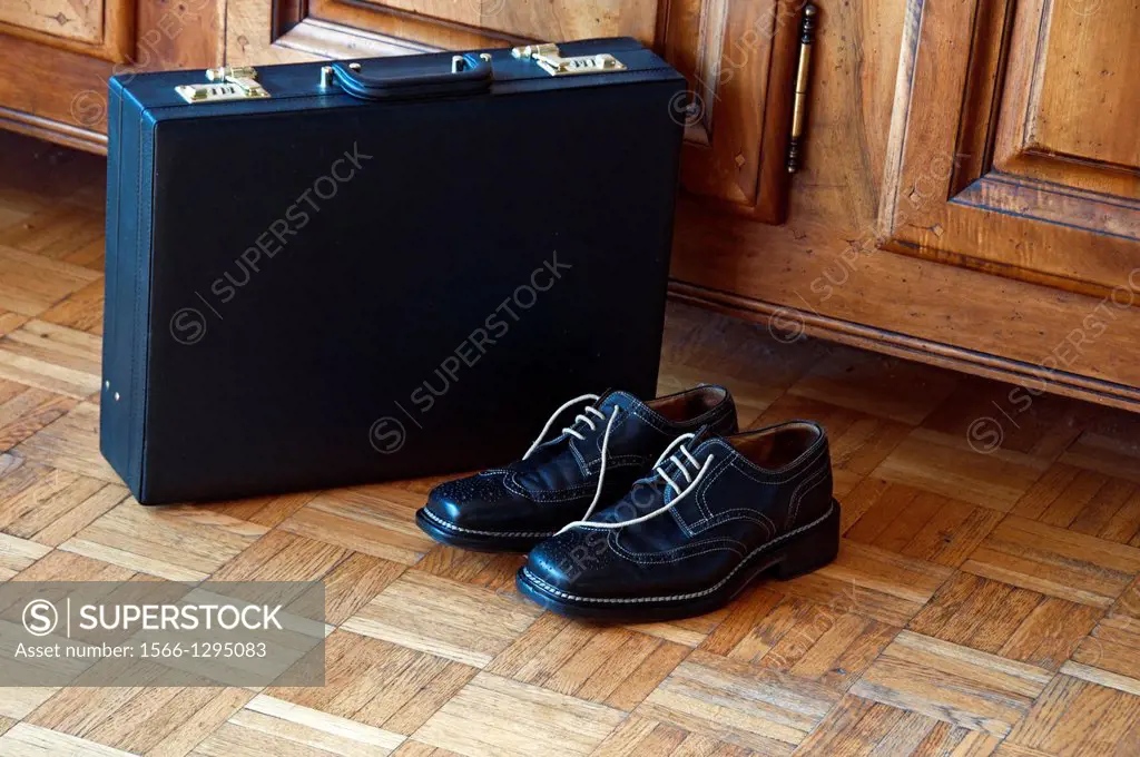 men´s black shoes and a briefcase, on the wooden floor, home, after work, private life