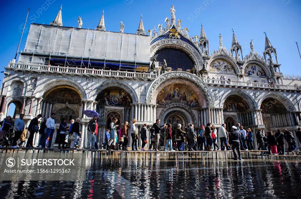 Tourists walking in front of the St. Mark´s Basilica during the ´Acqua Alta´ season in Venice, Italy.
