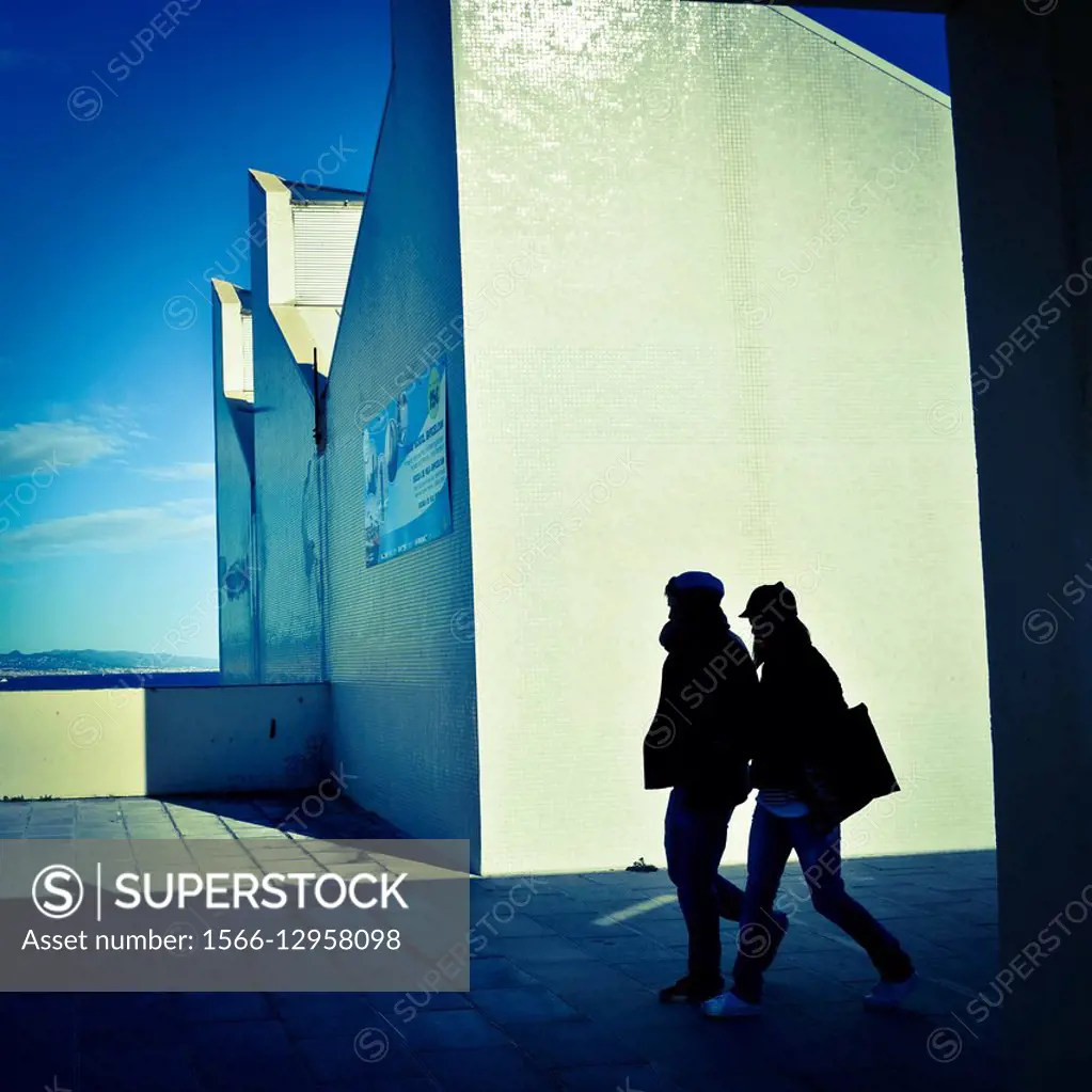 Silhouette of two people walking, white wall. Moll de Gregal, Vila Olímpica, Barcelona, Catalonia, Spain.