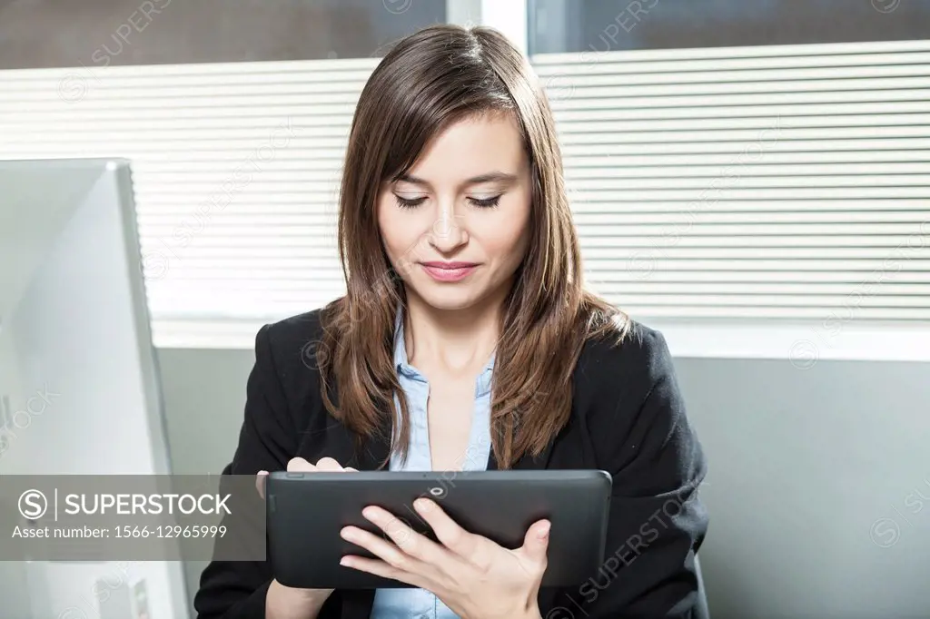 Woman in office working on tablet.