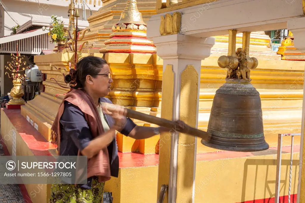 Woman ringing bell at Botataung Pagoda, Buddhas First Sacred Hair Relic Pagoda, Yangon, (Rangoon), Myanmar, (Burma).