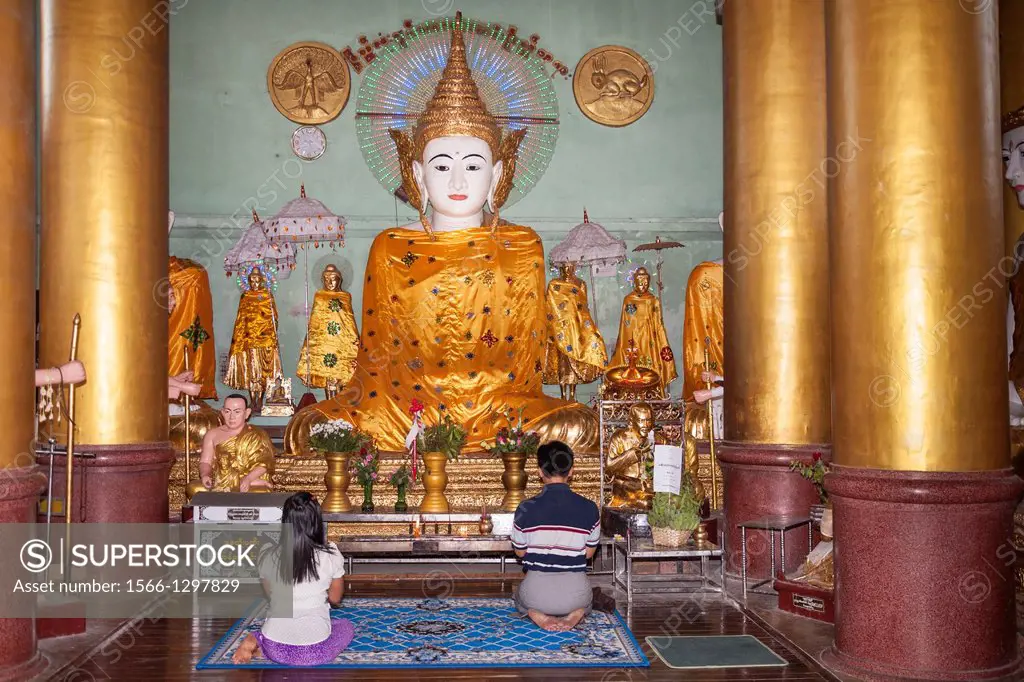 Worshippers praying inside a prayer hall at Shwedagon Pagoda, Yangon, (Rangoon), Myanmar, (Burma).