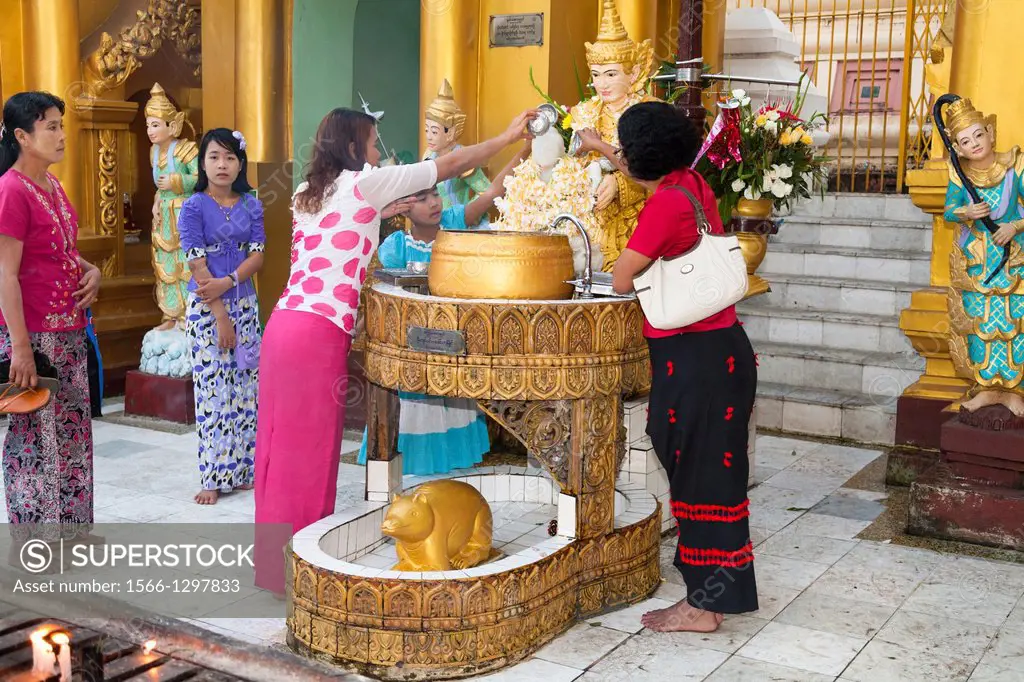 Worshippers pouring water onto a religious statue at Shwedagon Pagoda, Yangon, (Rangoon), Myanmar, (Burma).
