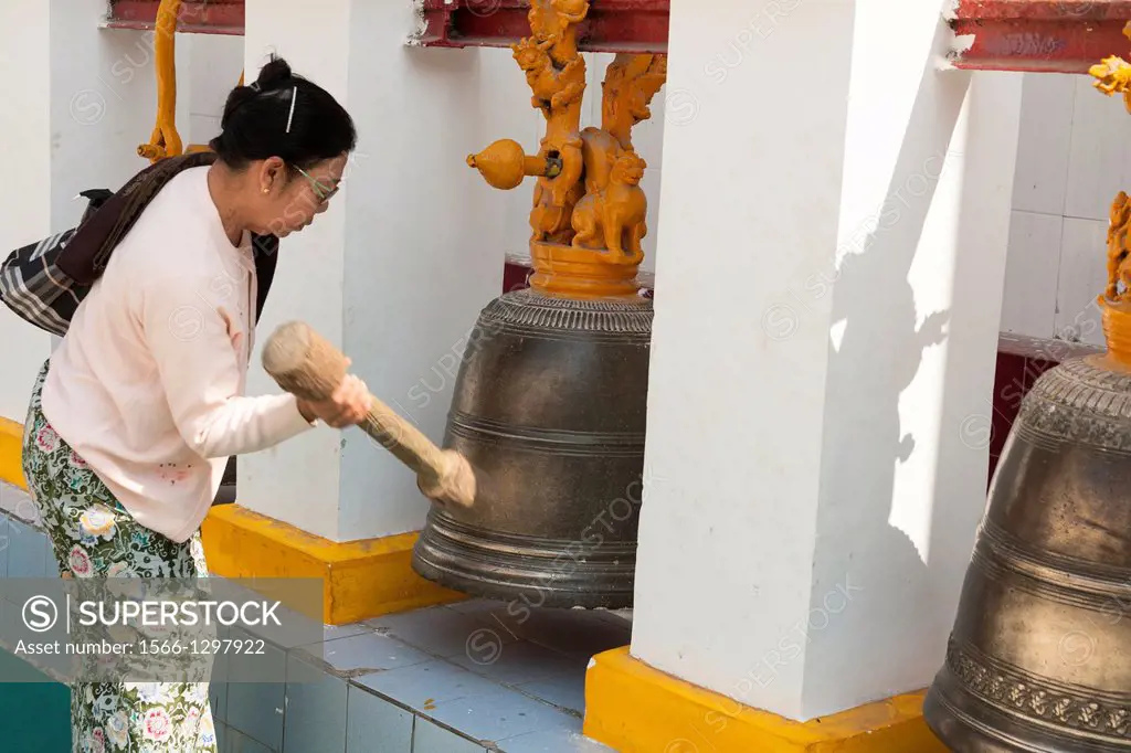 Woman ringing a bell, Mahamuni Pagoda, Mandalay, Myanmar, (Burma).