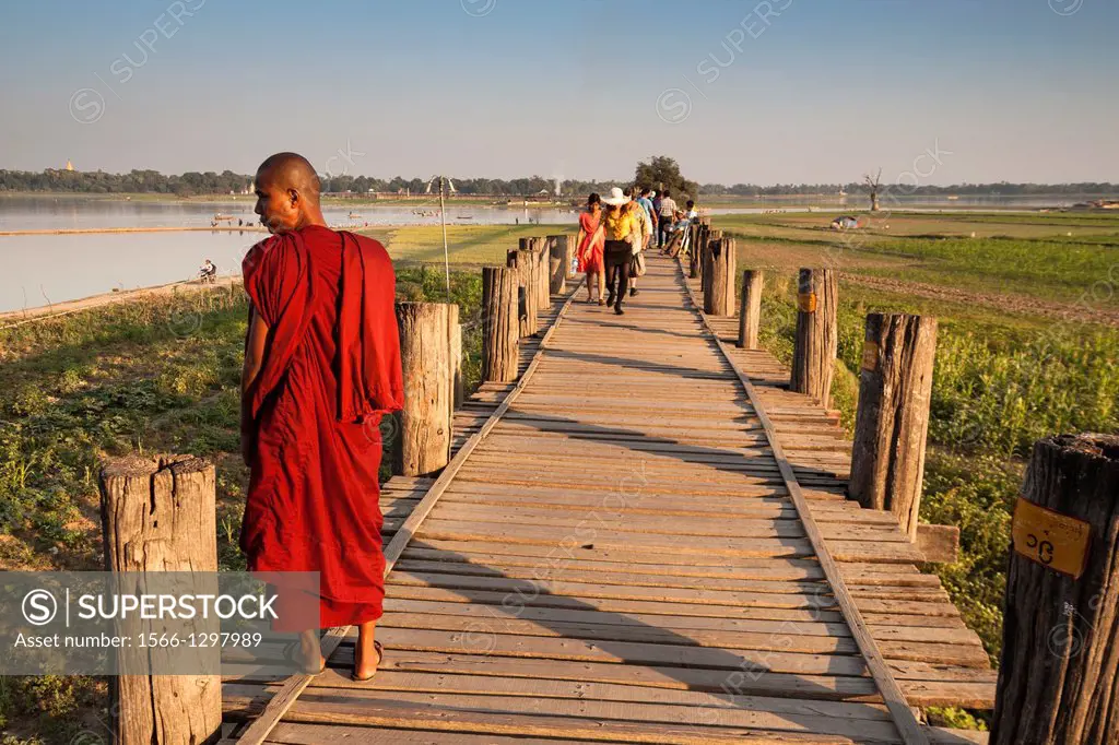 Buddhist monk standing on U Bein wooden bridge, Taungthaman Lake, Amarapura, Mandalay, Myanmar, (Burma).