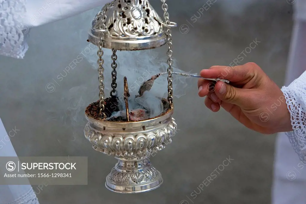 Altar boy looking with a silver spoon incense in a censer during a procession of holy week, Andalucia, Spain.