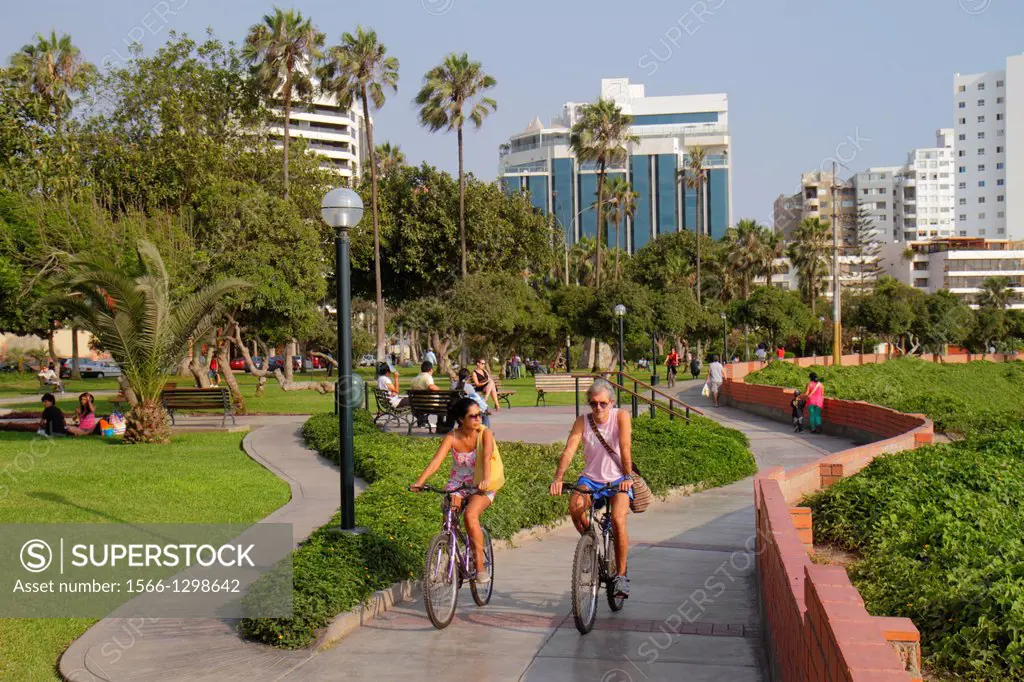 Peru, Lima, Miraflores, Malecon de la Reserva, Parque Domodossola, urban park, landscaping, trees, green space, Hispanic, man, woman, riding, bicycle,...