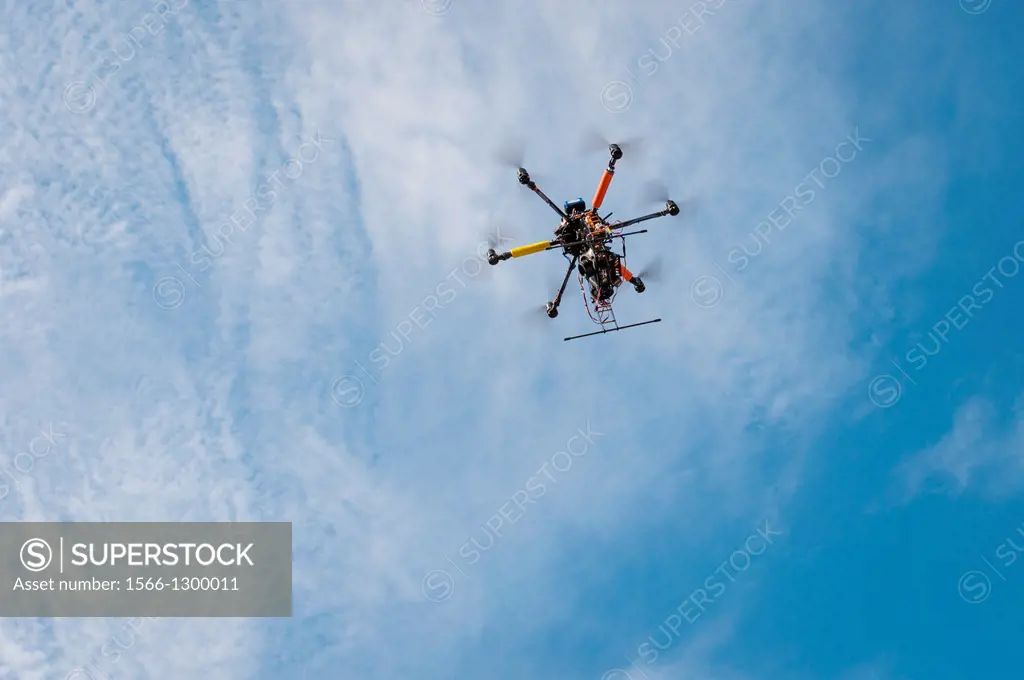 A drone with a camera hovers overhead in the sky.