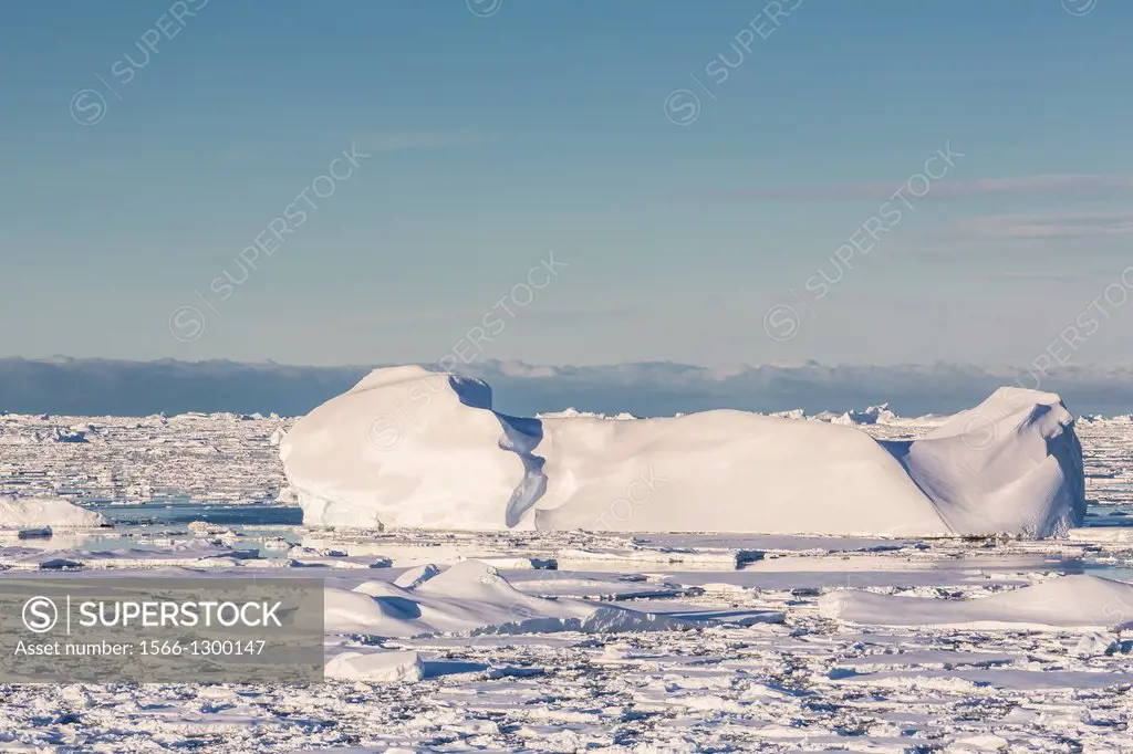 Huge Iceberg amongst sea ice near Pleaneau Island, western side of the Antarctic Peninsula, Southern Ocean.