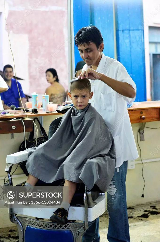 A boy is cut his hair by hair dresser in Remedios, Cuba.