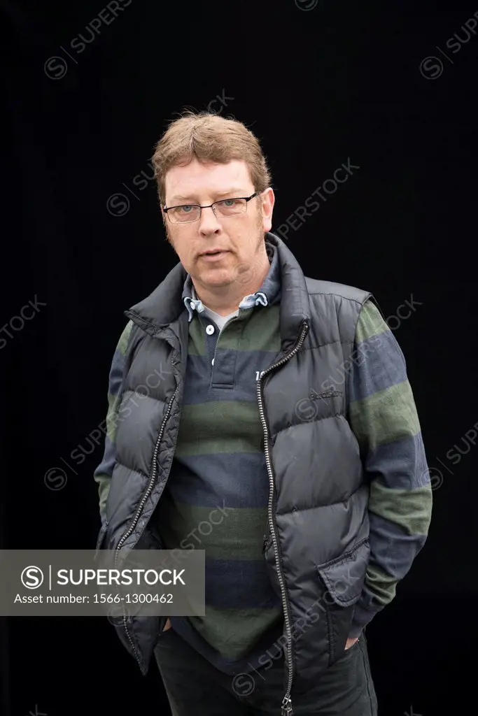 Tilburg, Netherlands. Self-portrait of a middle aged man with glasses against a black background. Portrait session on the weekly market.