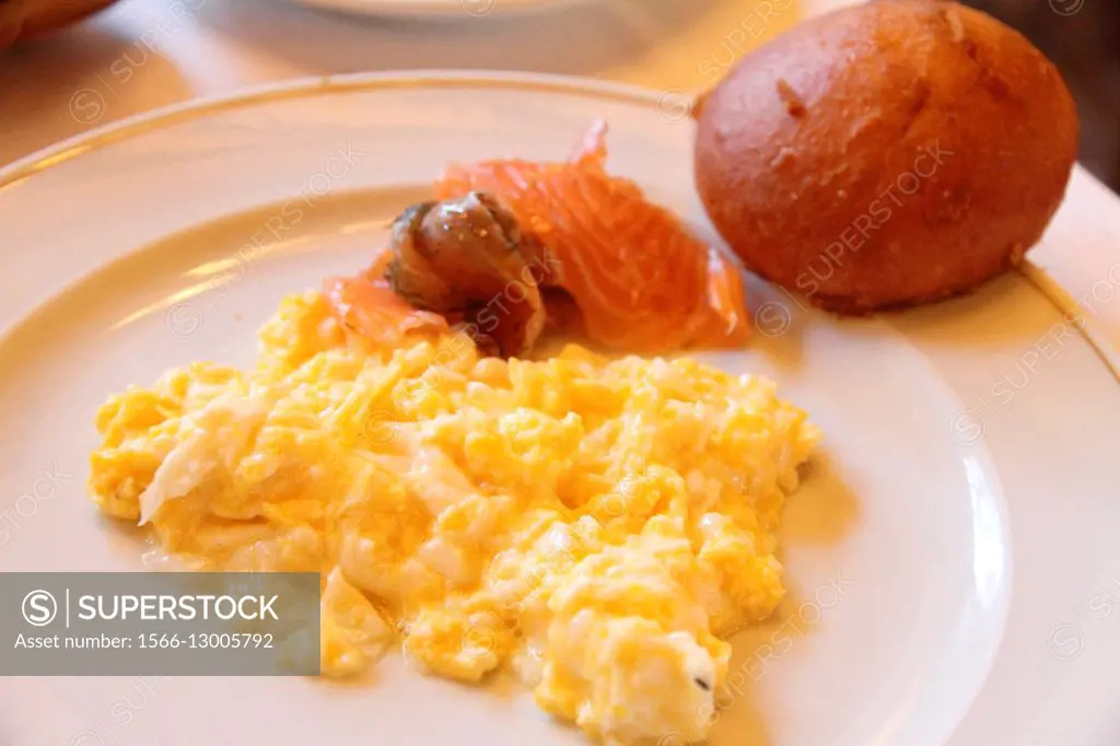 Scrambled eggs salmon and bread on plate.
