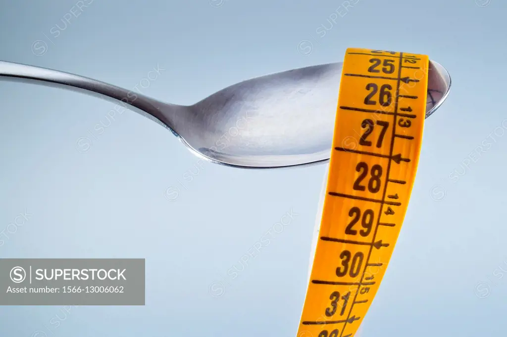 Spoon and measuring tape. Concept of food and weight loss.