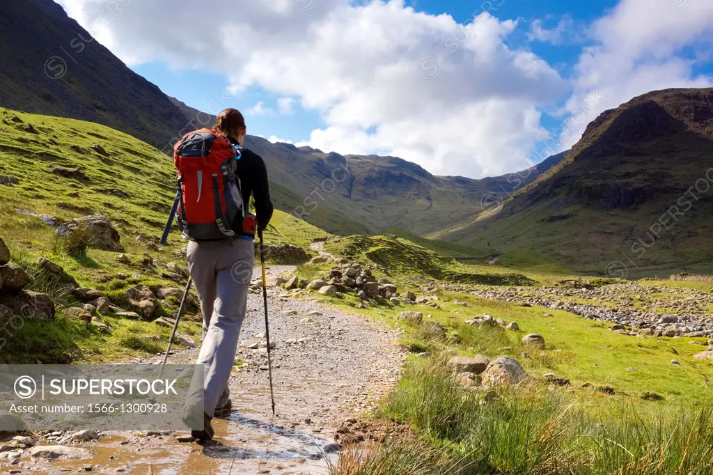 A walker approaches Seathwaite Fell in the Lake District, Cumbria, UK on a bright spring day.