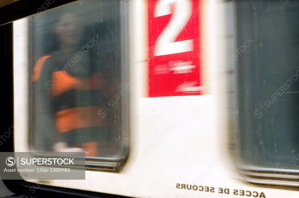 unrecognizable blurred image of woman looking through a window of a moving train in second class