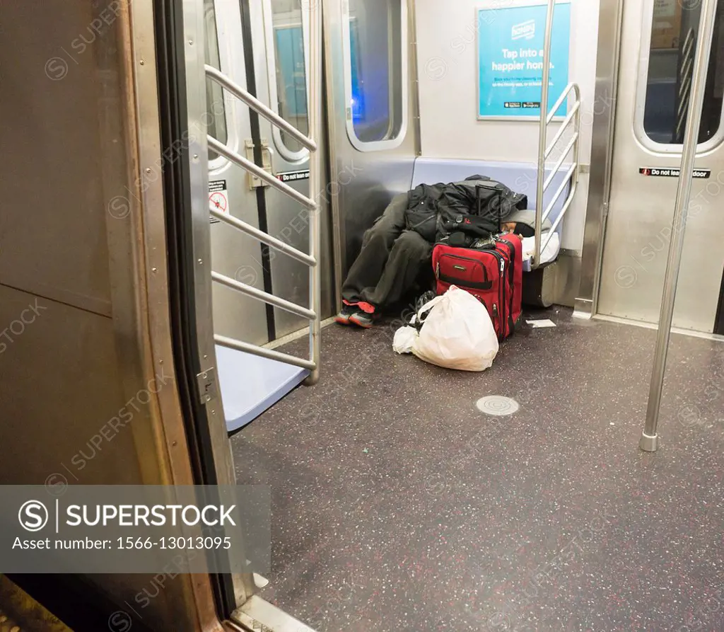 A homeless individual sleeps on the subway in New York