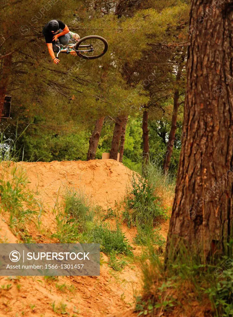 Montain Biker Blake Samson doing a 360 Table over a dirt jump in a forest near the South of France.