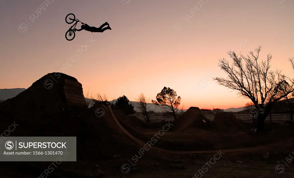 Mountain Biker, Sam Reynolds doing a superman seatgrab over a jump while the sn sets.