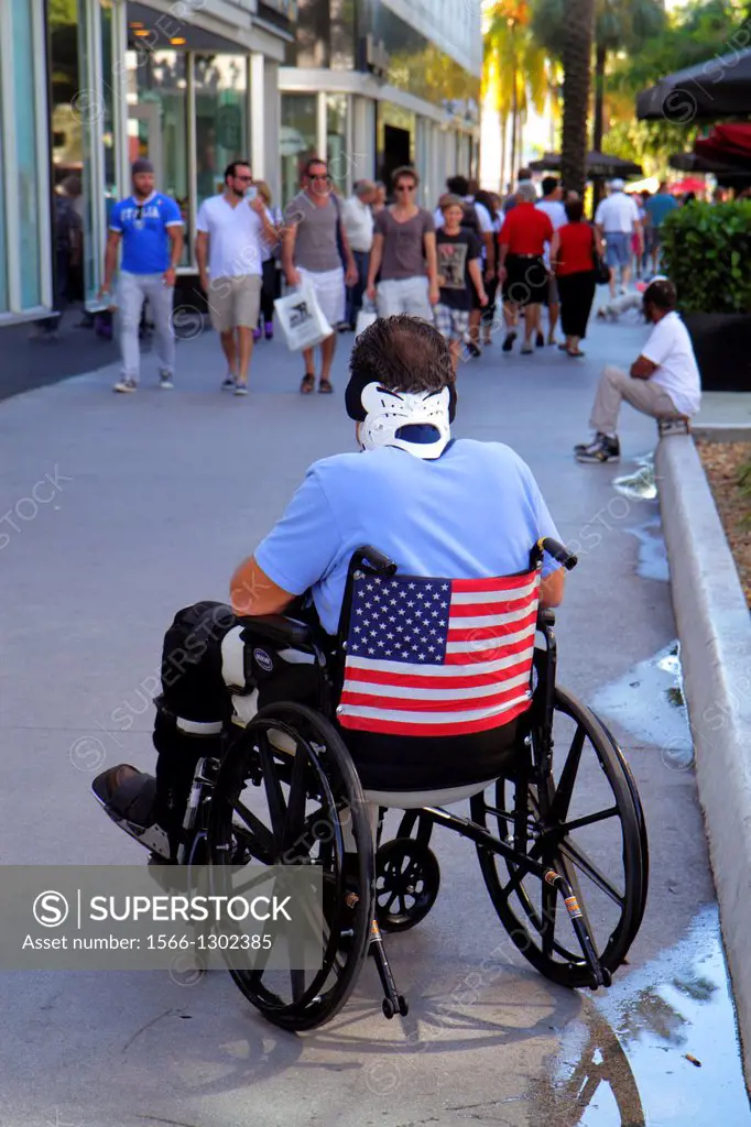 Florida, Miami Beach, Lincoln Road, pedestrian mall, man, wheelchair, disabled, neck brace, flag,.