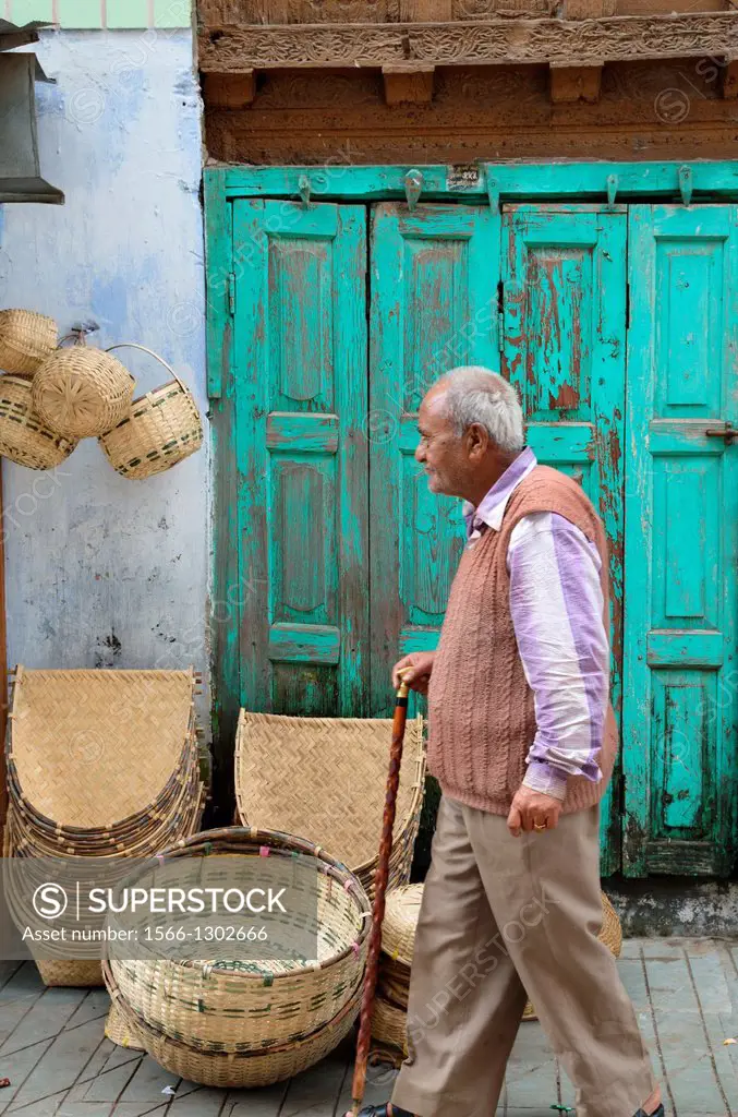 An elderly man walks past baskets for sale, Almora, India.