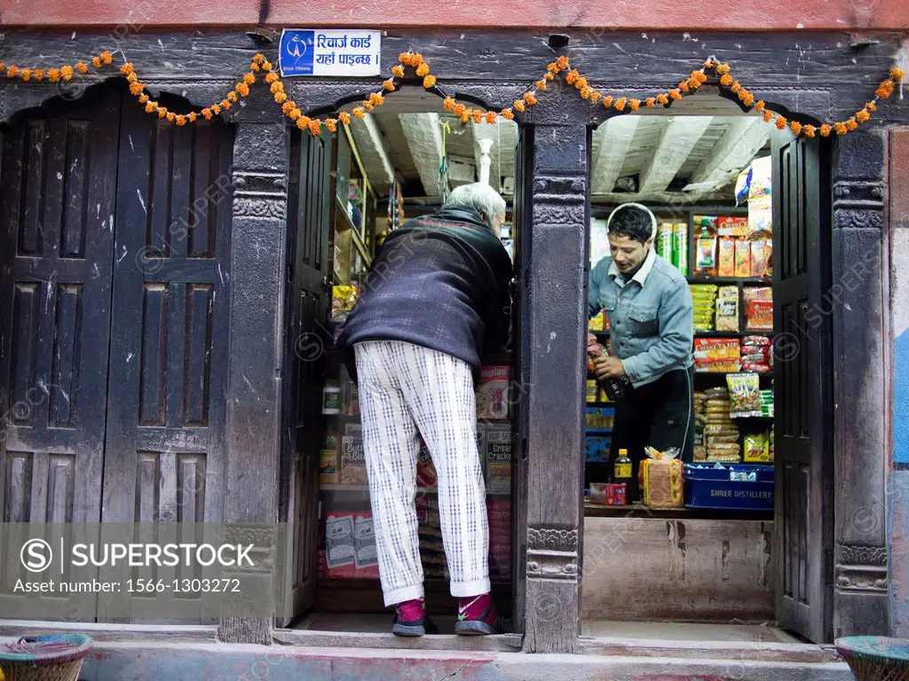 A mans stops at a small shop to buy a few goods in Patan, Nepal.