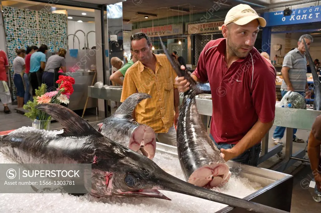 A fishmonger prepares a swordfish for filleting, in the covered market in Kalamata, Messinia, Southern Peloponnese, Greece.