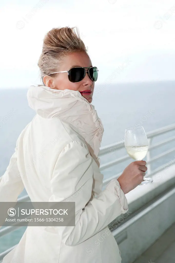 Blonde woman holding wine glass on balcony - South Florida, USA.