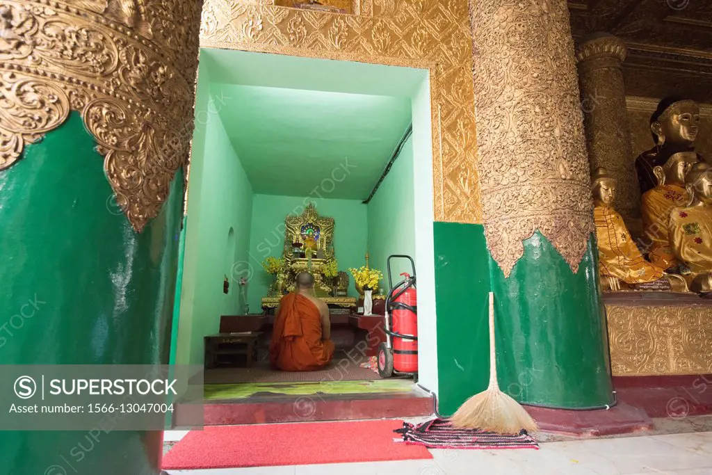 A monk prays in one of the many chapels to Buddha within the Shwedagon Pagoda complex.