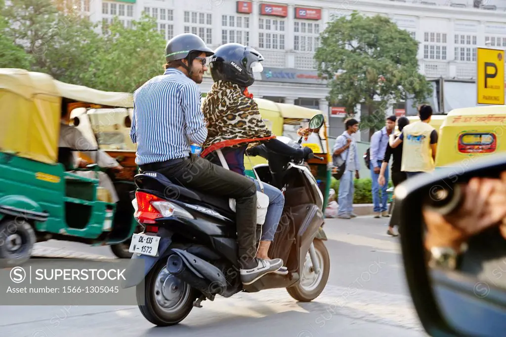 A young modern couple rides a scooter in Delhi.