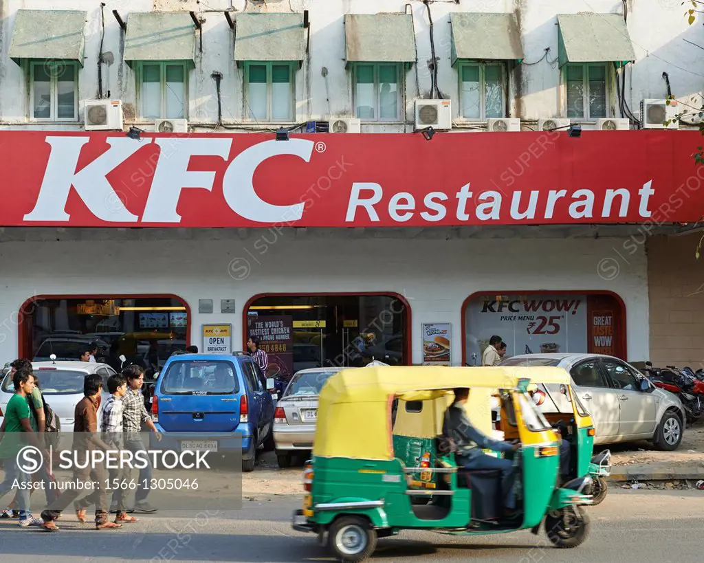 Tuk Tuks and locals whizzing past a Kentucky Fried Chicken (KFC) restaurant in Delhi.