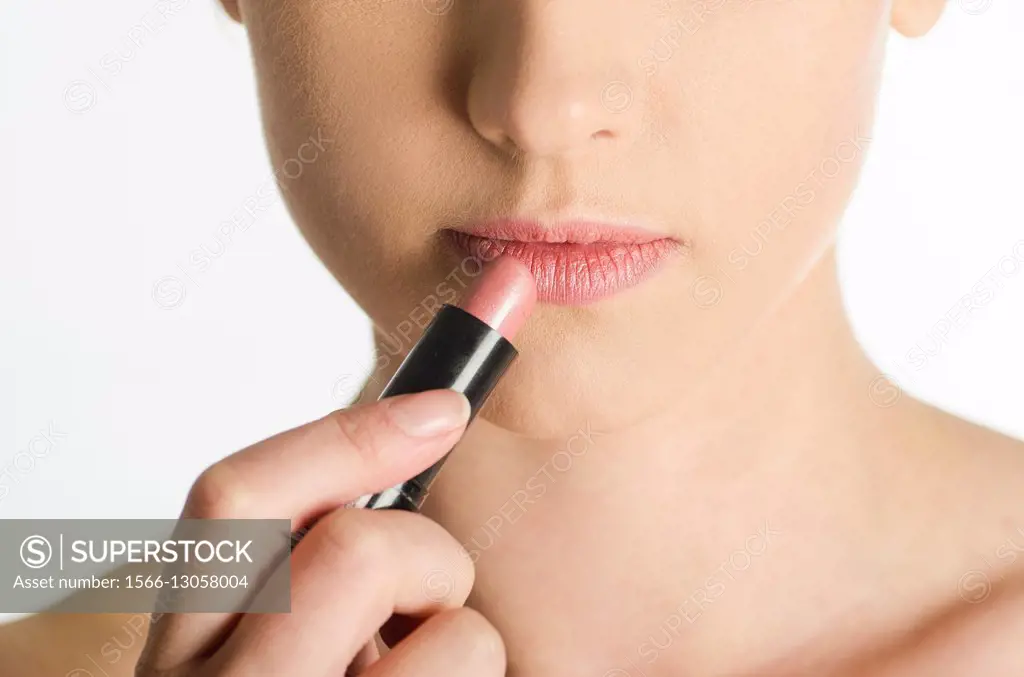 Close up of a young woman applying lipstick.